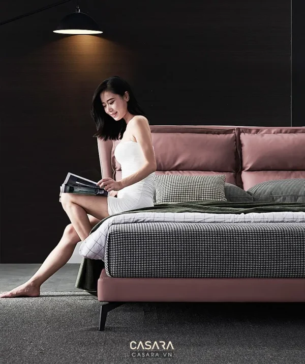 Người phụ nữ thư giãn đọc sách trên chiếc giường màu hồng pastel hiện đại.