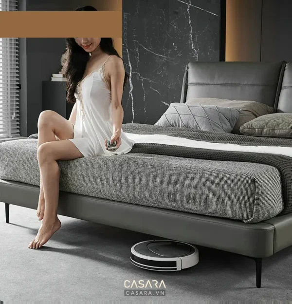 Người phụ nữ thư giãn trên giường với robot hút bụi.