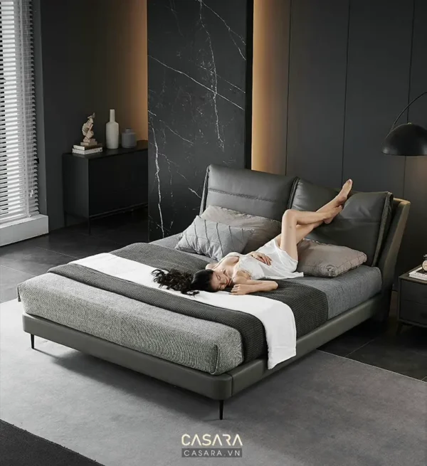 Phòng ngủ tối giản, sang trọng với giường màu xám và người phụ nữ thư giãn.
