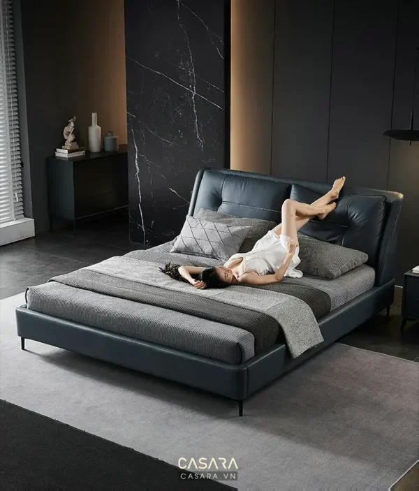 Phòng ngủ sang trọng với giường màu xanh đen và người phụ nữ thư giãn.