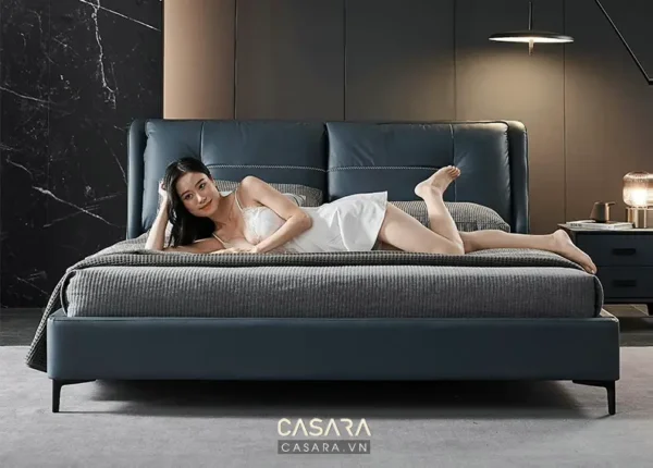 Người mẫu thư giãn trên chiếc giường màu xanh navy sang trọng.