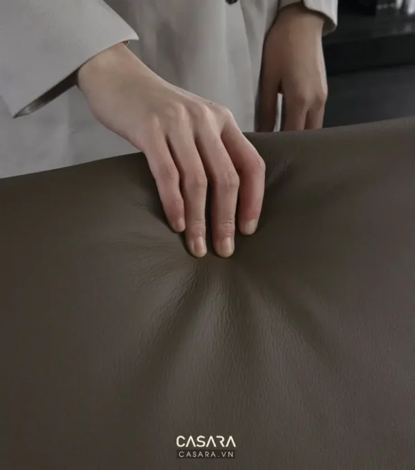 Bàn tay chạm vào bề mặt da lộn màu nâu, thể hiện chất liệu mềm mại.