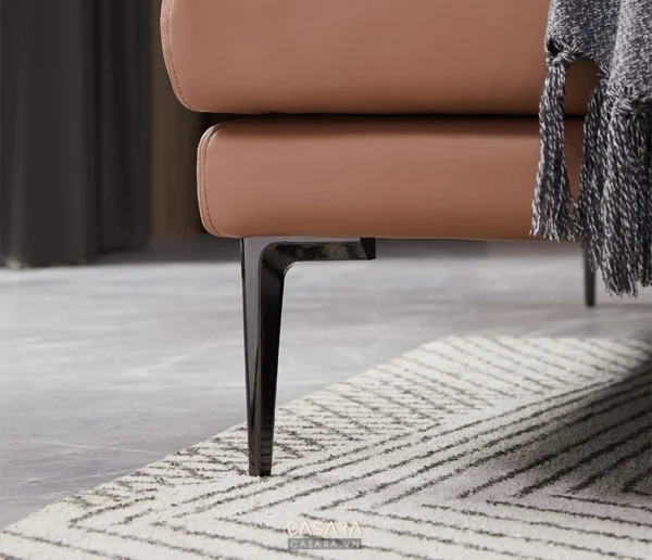 Góc nhìn cận cảnh phần chân và tay ghế sofa da màu cam đất hiện đại.