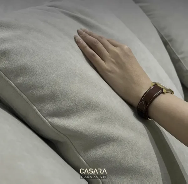 Một bàn tay đặt trên gối vải nhung xám.