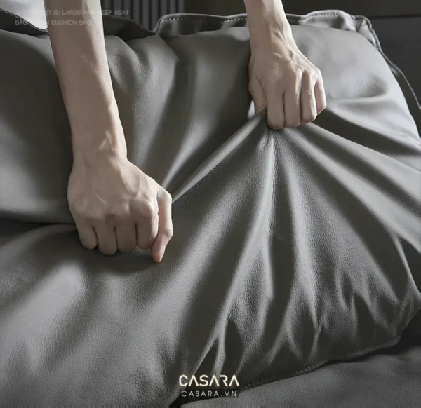 Bàn tay đang vuốt nhẹ tấm vải màu xám đậm.