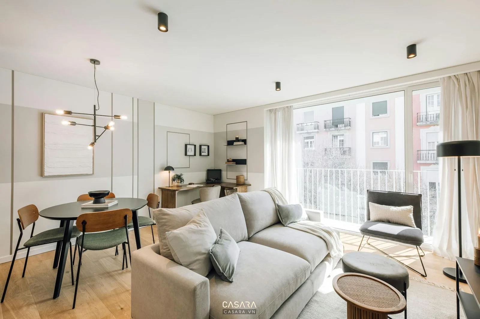 Phòng khách căn hộ nhỏ liên thông bàn ăn, sofa sáng màu, cửa kính lớn và đèn thả giúp khu chung thoáng và dễ dùng.