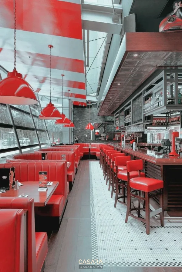 Nhà hàng tông đỏ với dãy ghế booth, quầy bar và đèn thả trần