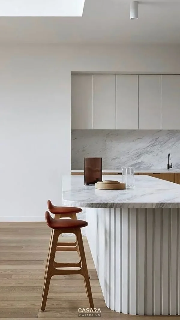 Góc đảo bếp pantry trắng với ghế gỗ nâu cho chủ đề nội thất chung cư 2 phòng ngủ Góc đảo bếp trắng phù hợp phần kiểm tra bếp và bàn ăn trong căn hộ. nội thất chung cư 2 phòng ngủ chung cư căn hộ phòng khách bếp tủ bếp phòng bếp phòng ngủ giường tủ áo công năng ánh sáng vật liệu bố trí Casara https://casara.vn/