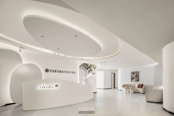 Ảnh quầy lễ tân spa trắng bo cong với logo và sofa chờ do Casara tuyển chọn cho thư viện thiết kế nội thất.