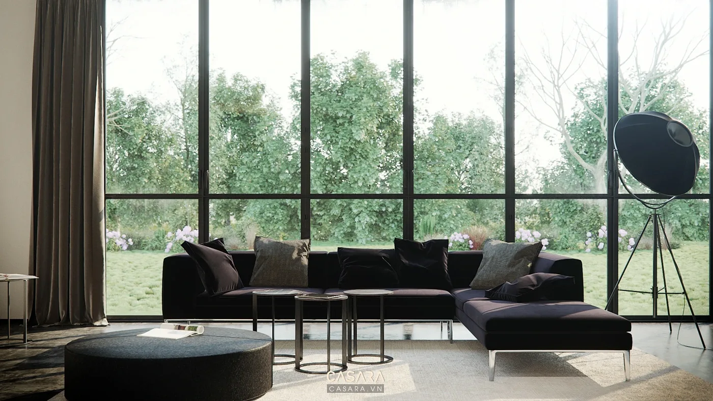 Sofa góc màu đen cạnh cửa kính lớn và bàn trà tròn trong phòng khách