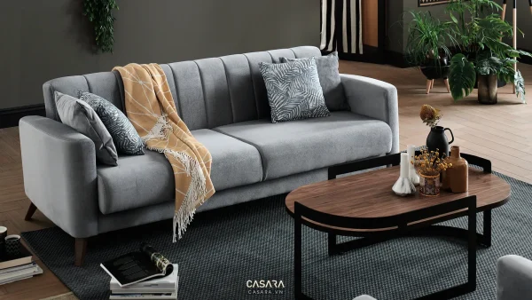 Sofa vải xám đặt cạnh bàn trà gỗ trong phòng khách có cây xanh