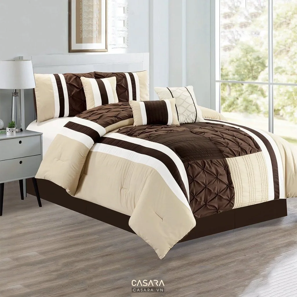 Giường ngủ cạnh cửa sổ với bộ chăn ga sọc nâu trắng và ánh sáng nhẹ