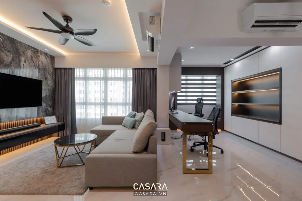 Phòng khách hiện đại với sofa sáng màu, kệ tivi, bàn làm việc và hệ tủ âm tường