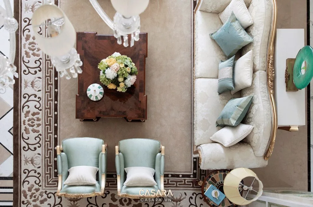 Phòng khách nhìn từ trên xuống với sofa cong, bàn trà gỗ và hai ghế bành xanh nhạt