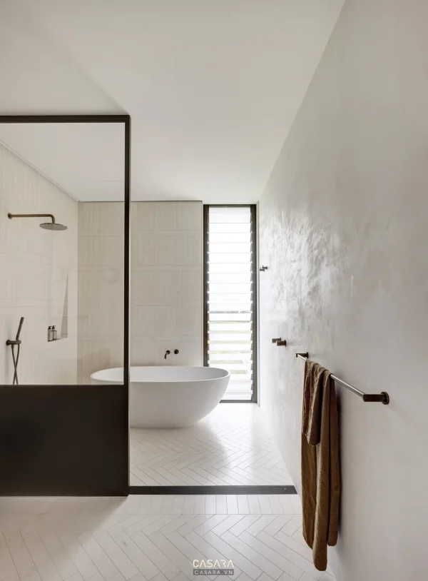 Ảnh phòng tắm trắng tối giản với bồn nằm và sen đen do Casara tuyển chọn cho thư viện thiết kế nội thất.