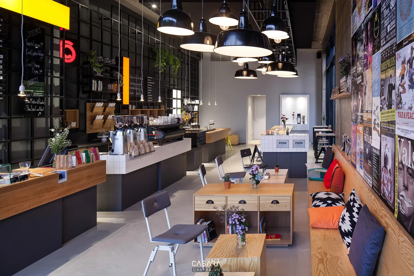 Quán coffee buổi tối có đèn thả ánh sáng vàng bàn ghế cafe logo trên tường ly cà phê và nội thất ấm áp
