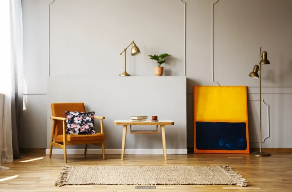 Phòng khách nhỏ có sofa vải xám, bàn trà gỗ, ghế đơn và ánh sáng tự nhiên