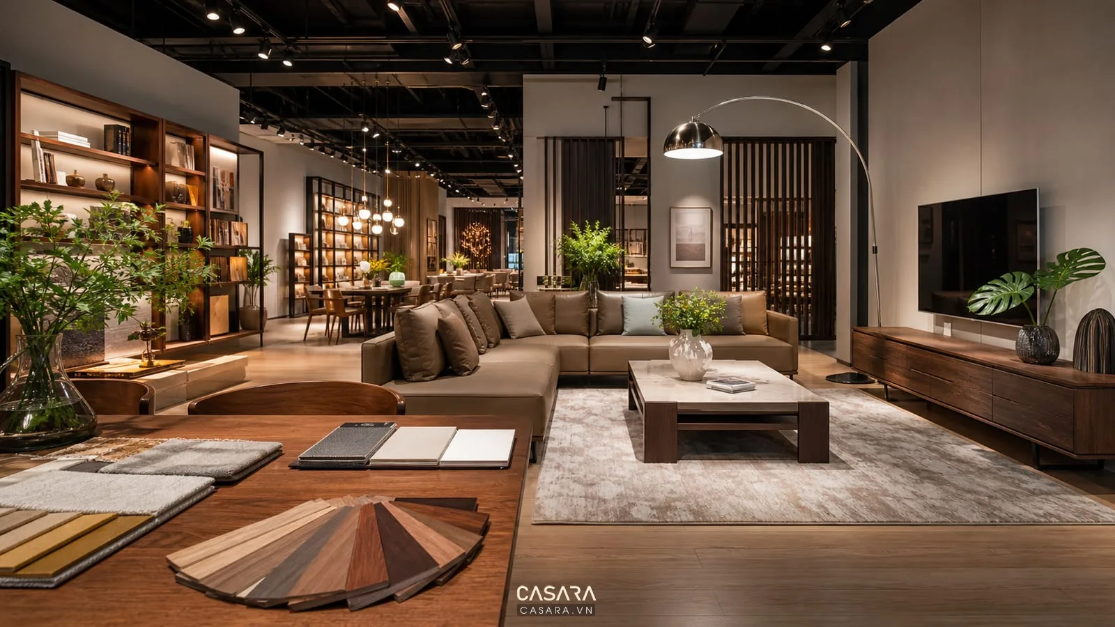 Showroom nội thất cao cấp với phòng khách mẫu, sofa, bàn trà, kệ tivi, thảm, đèn và bàn tư vấn vật liệu.