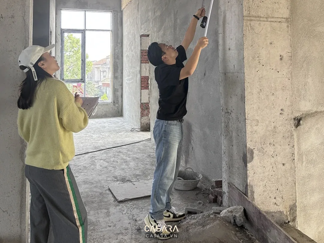 Nhân sự đo đạc tường trong công trình biệt thự đang hoàn thiện