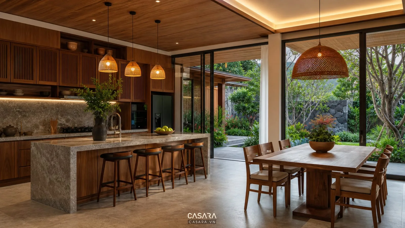 Khu bếp và bàn ăn biệt thự Lâm Đồng với tủ bếp gỗ, đảo bếp đá, đèn thả và cửa kính sân vườn