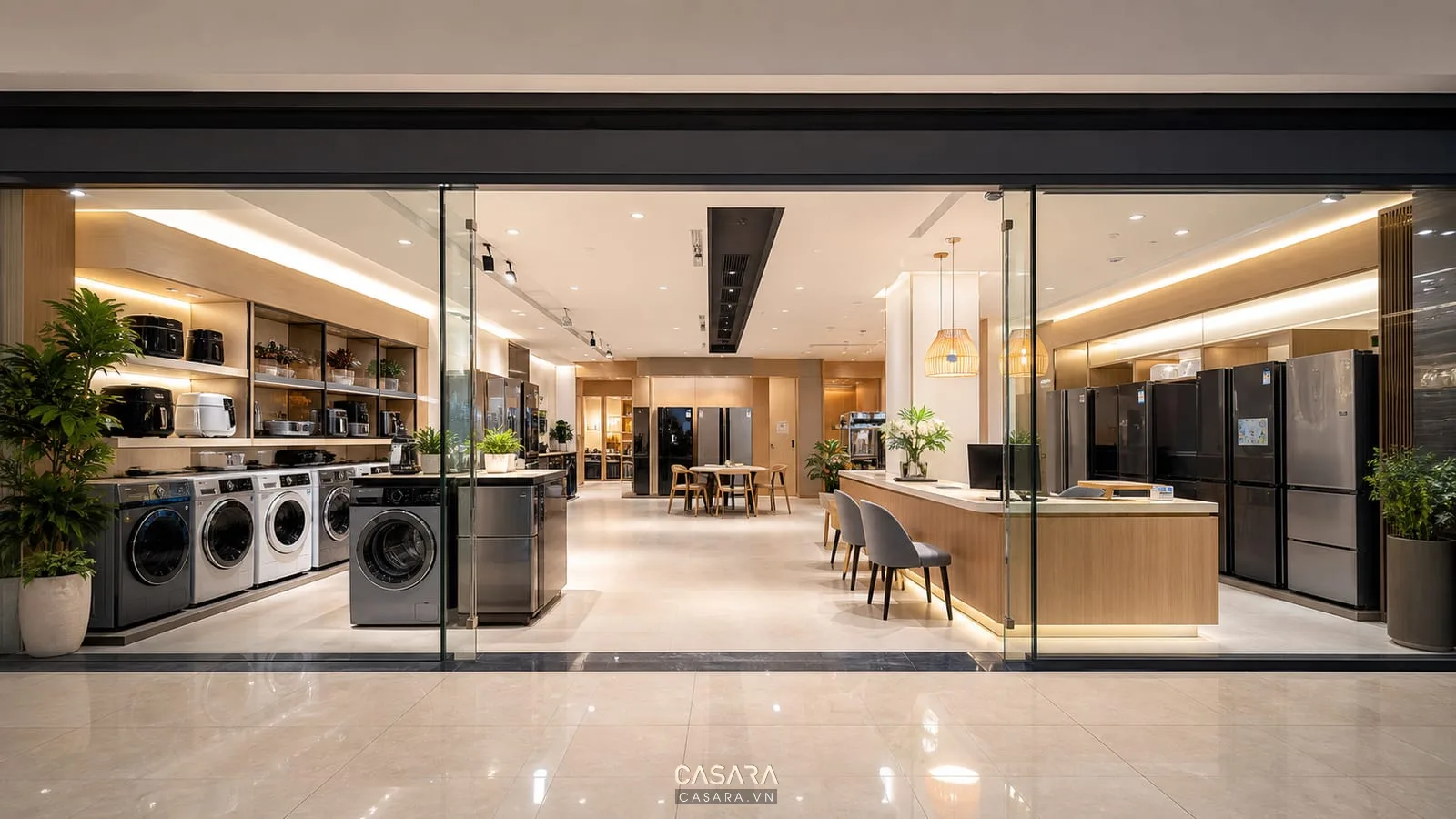 Cửa kính showroom đồ gia dụng trong trung tâm thương mại với máy giặt, tủ lạnh, nồi chiên không dầu, quầy tư vấn và lối đi rộng.