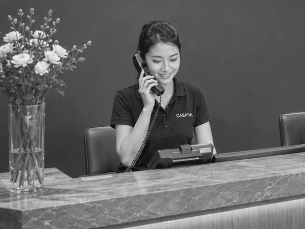 Nhân viên lễ tân nghe điện thoại tại quầy tiếp khách