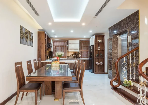 Phòng bếp ăn hiện đại với bàn ghế gỗ, tủ bếp và cầu thang bên cạnh