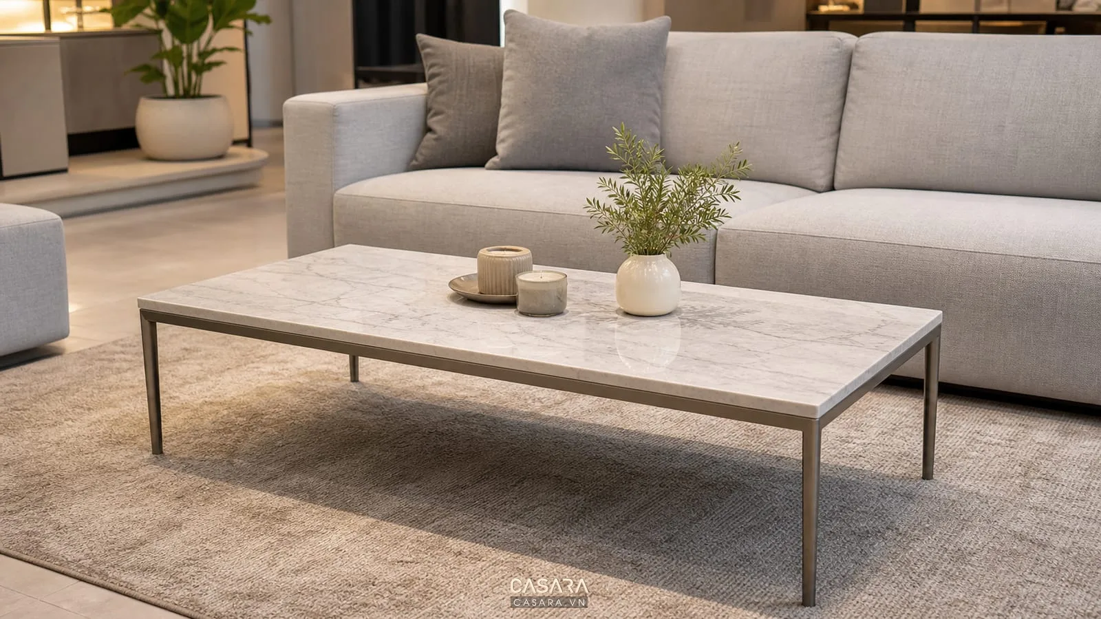 Bàn trà phòng khách đơn giản mặt đá vân nhẹ, chân kim loại mảnh, sofa xám nhạt và thảm trung tính