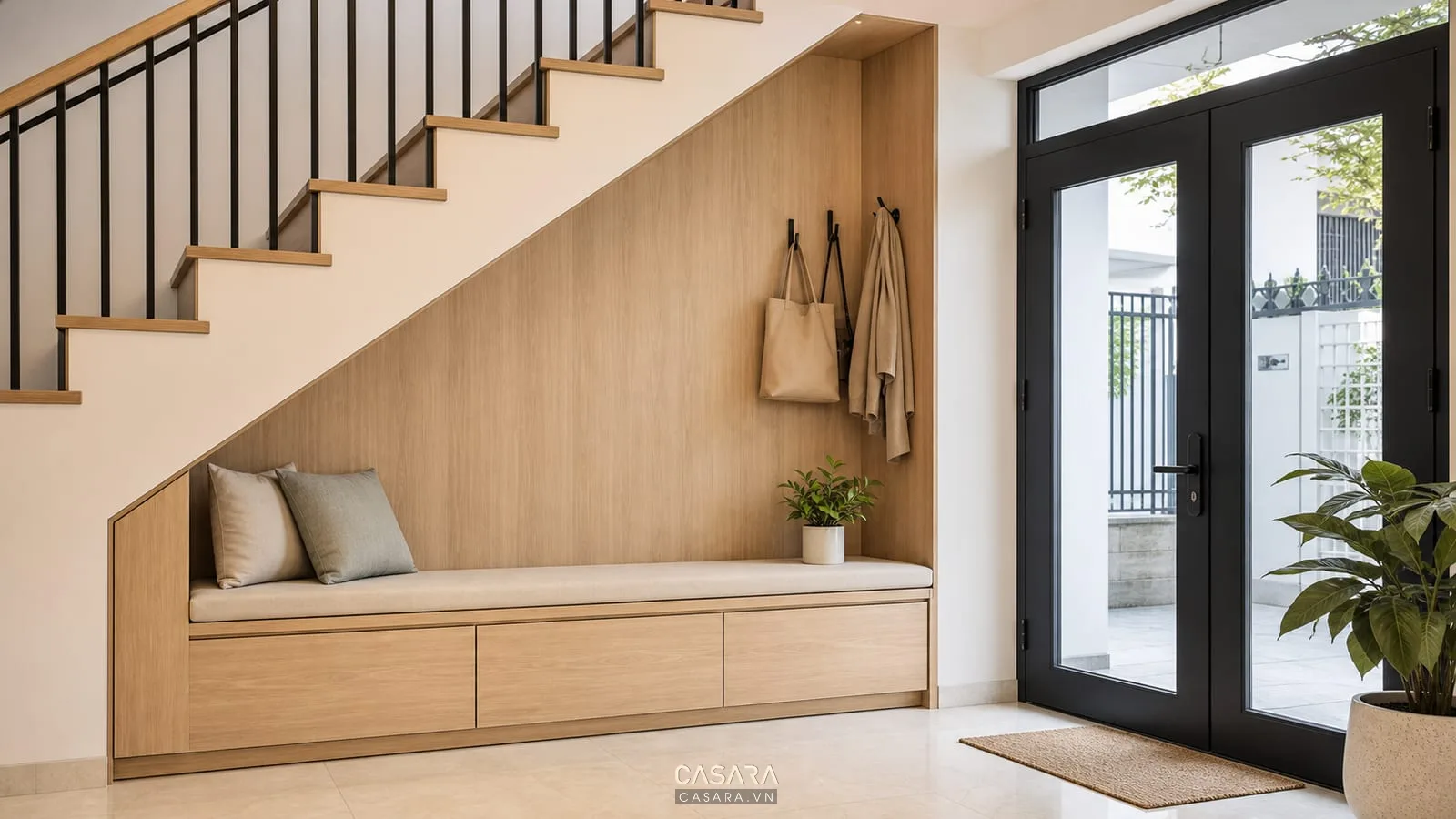 Gầm cầu thang làm ghế băng thay giày với tủ giày thấp cánh kín móc treo nhỏ cửa vào nhà phố vật liệu gỗ sáng