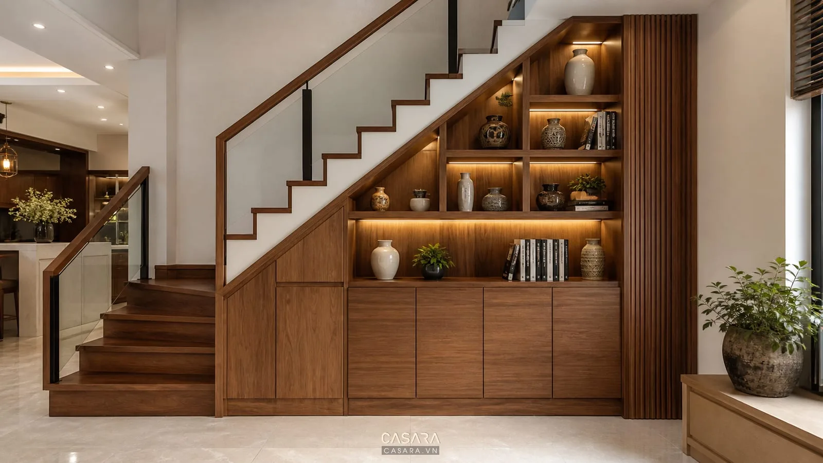 Trang trí gầm cầu thang đẹp với kệ mở gỗ sách bình gốm và đèn led hắt sáng