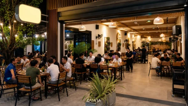 Quán nhậu đẹp với bàn ghế gỗ ánh sáng ấm bảng hiệu quán bia và khách ngồi theo nhóm