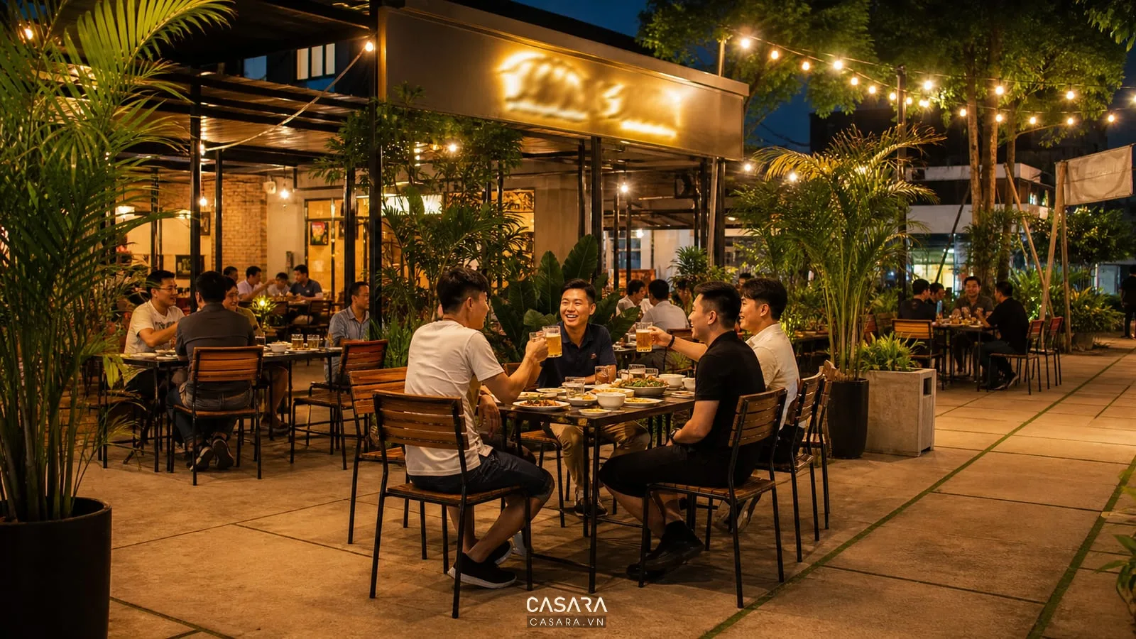 quán bia sân vườn có bàn ghế ngoài trời cây xanh và ly bia