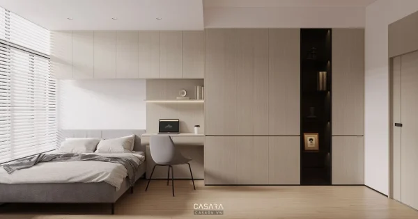 Phòng ngủ sáng màu có giường cạnh cửa sổ, bàn làm việc và hệ tủ âm tường