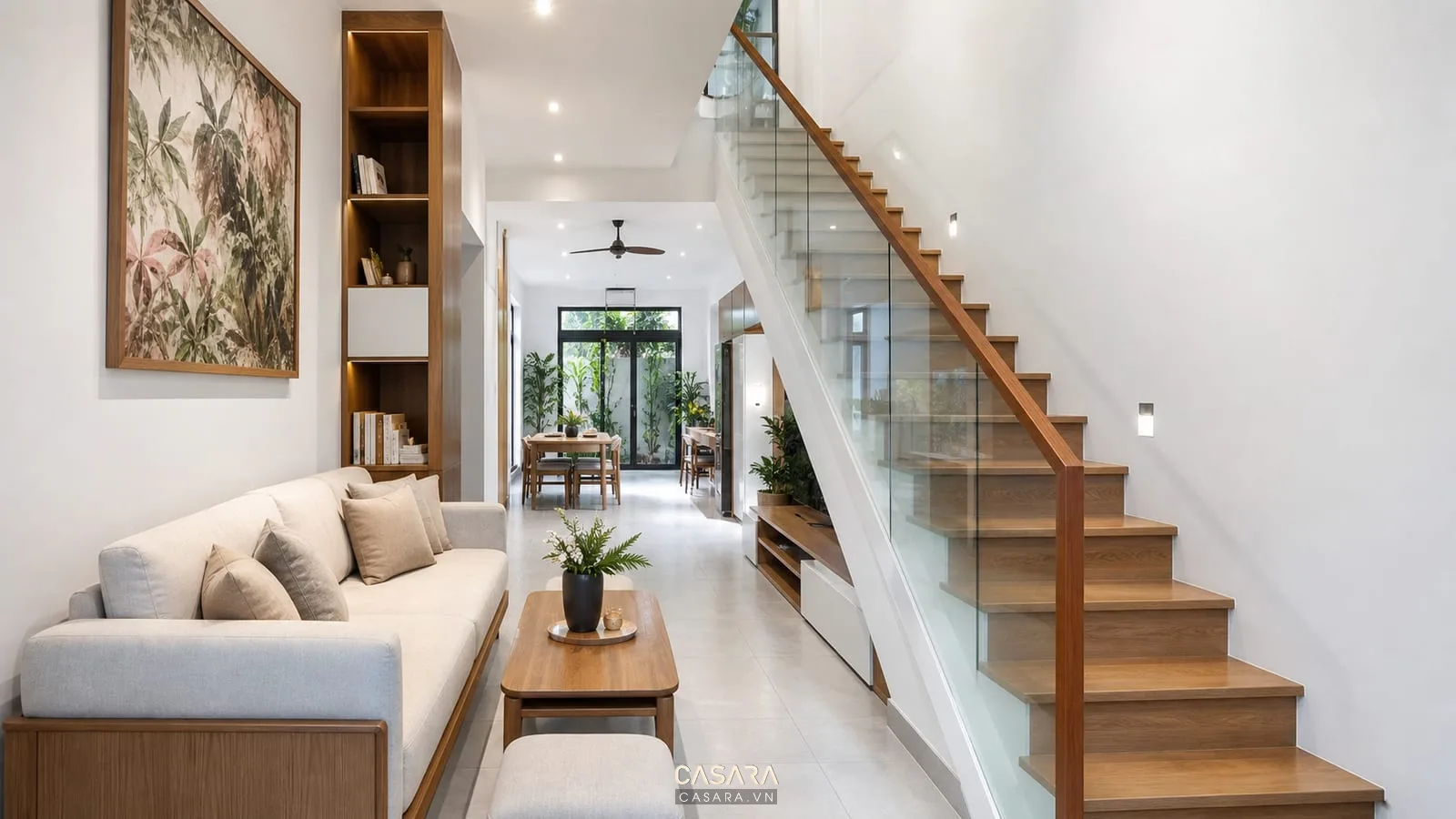 Cầu thang chữ L nhà ống hiện đại với chiếu nghỉ giữa tầng, lan can kính, bậc gỗ, giếng trời nhỏ, phòng khách và bếp liên thông
