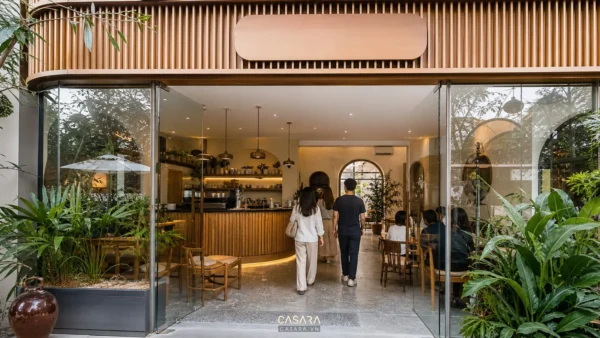 Quán cà phê đẹp có mặt tiền kính và quầy bar gỗ nhìn từ lối vào