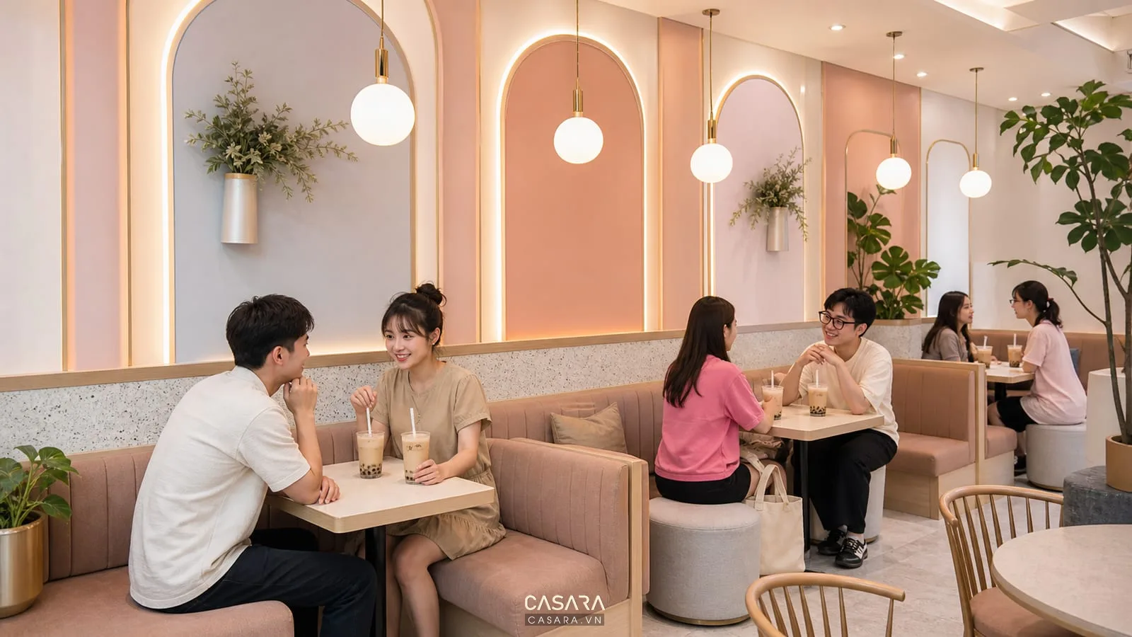 Khu ngồi quán trà sữa với ghế băng bọc nệm tường pastel và ly trà sữa trên bàn