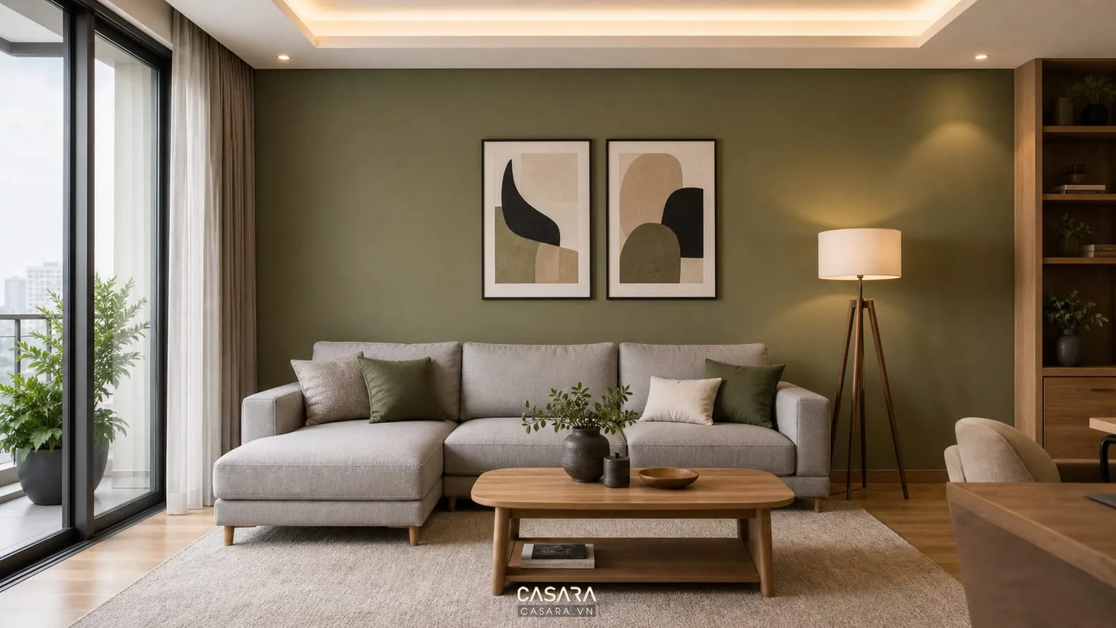Cách phối màu sơn phòng khách với tường xanh olive sau sofa, sofa xám sáng, tranh và bàn trà gỗ