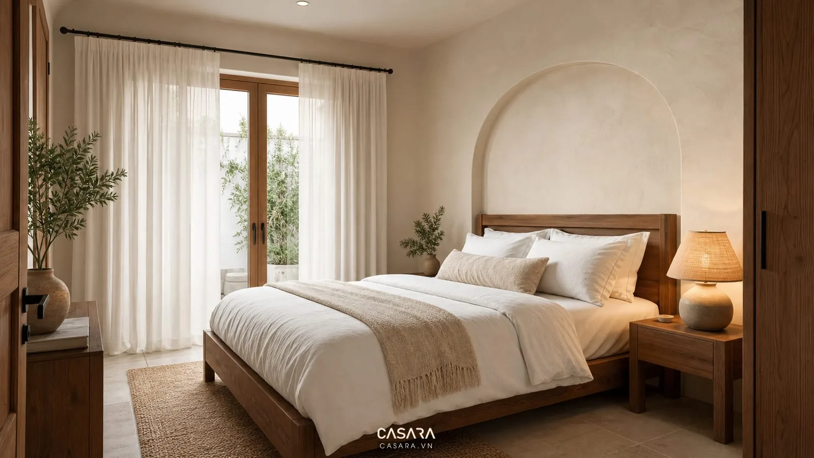 Phòng ngủ nhà phong cách địa trung hải với giường gỗ đầu giường bo cong rèm linen tường kem và đèn ngủ ấm
