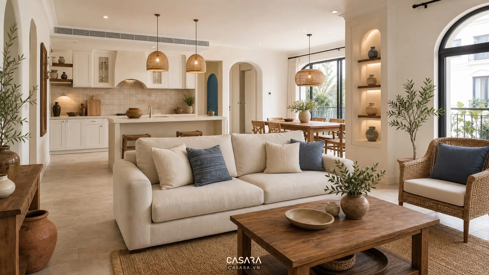Phòng khách bếp phong cách nội thất địa trung hải với sofa kem, tủ bếp trắng ngà, bàn ăn gỗ và đèn mây
