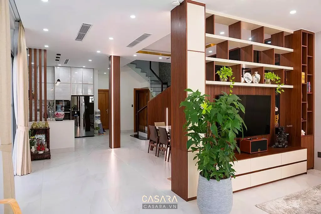 Phòng khách sáng rộng với kệ tivi gỗ, vách nan và chậu cây xanh