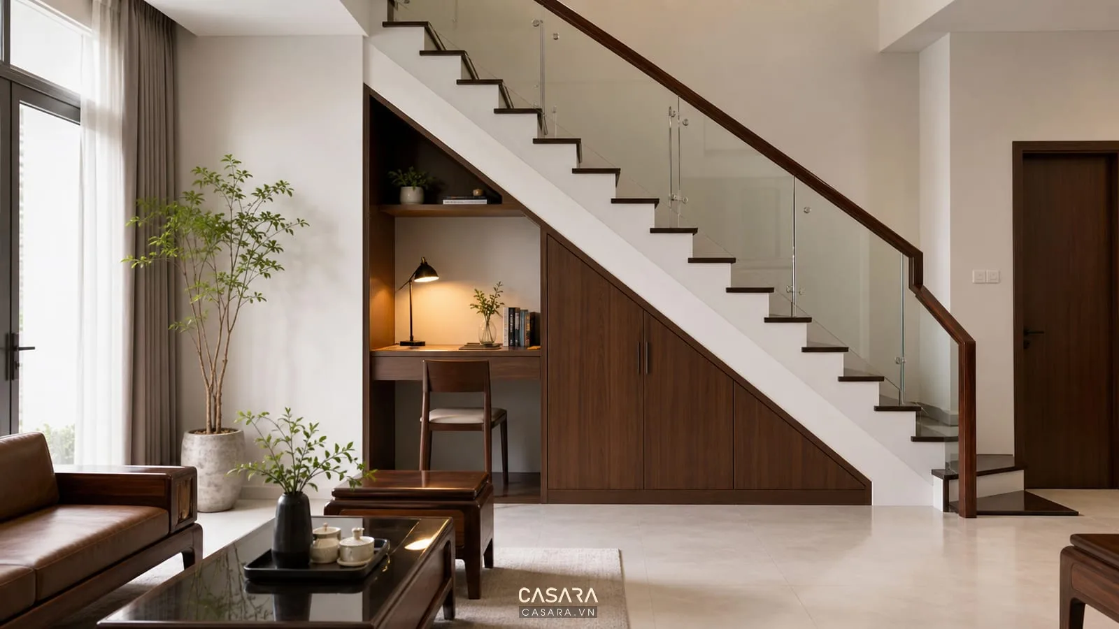 Thiết kế dưới gầm cầu thang làm góc làm việc nhỏ với bàn gỗ, ghế đơn, kệ sách, đèn bàn và cầu thang hiện đại trong nhà phố hẹp