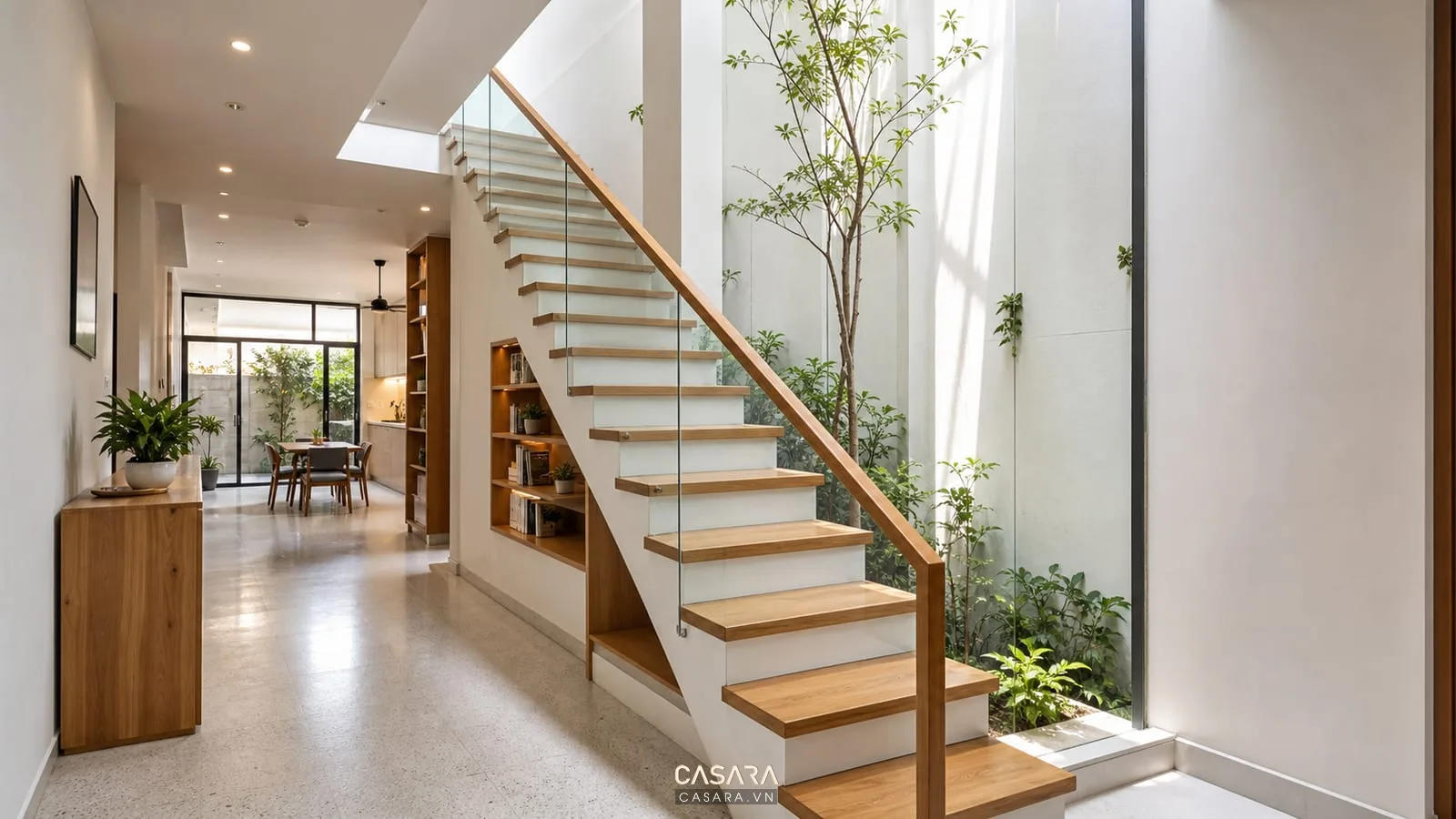 Cầu thang nhà ống 4m có giếng trời, bậc gỗ, lan can kính và ánh sáng tự nhiên giữa nhà