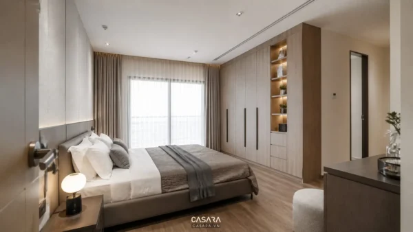 Phòng ngủ chung cư có giường đôi, rèm sáng và hệ tủ quần áo âm tường