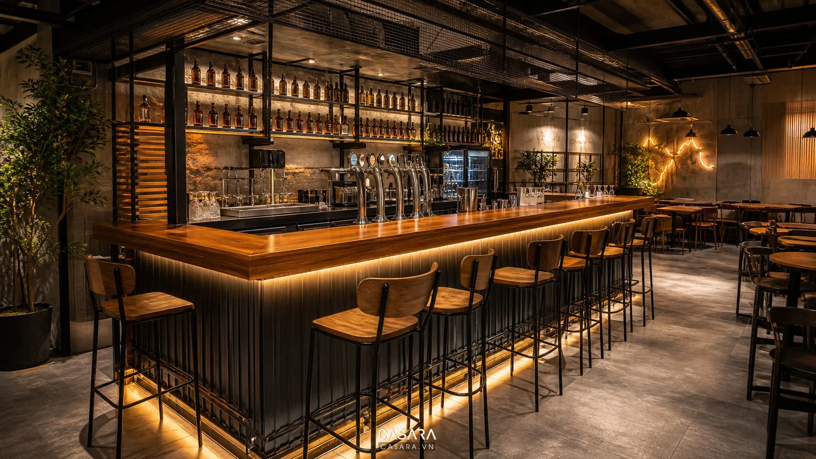 Quán nhậu độc lạ có quầy bar bia, ghế cao, mặt quầy gỗ, kệ chai phía sau, đèn neon nhỏ và phong cách hiện đại trẻ trung