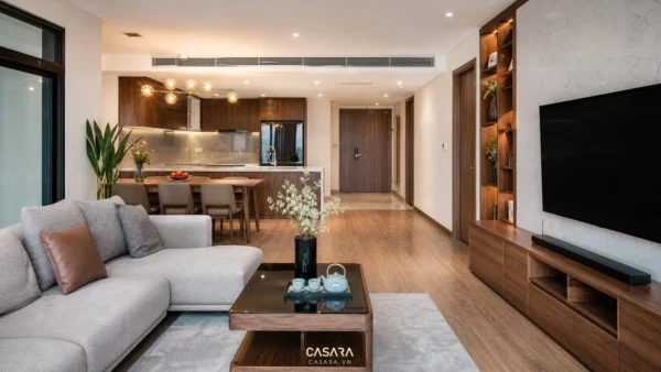 Phòng khách liền bếp chung cư với sofa xám, bàn ăn gỗ và kệ tivi âm tường