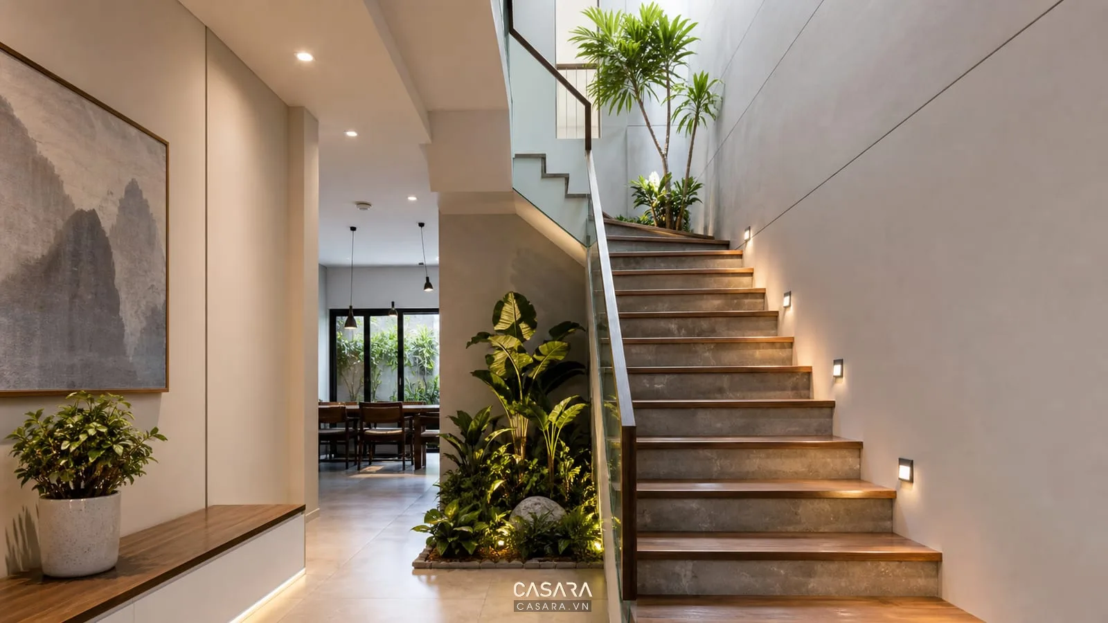 Cầu thang nhà ống có giếng trời cây xanh và đèn ánh sáng ấm