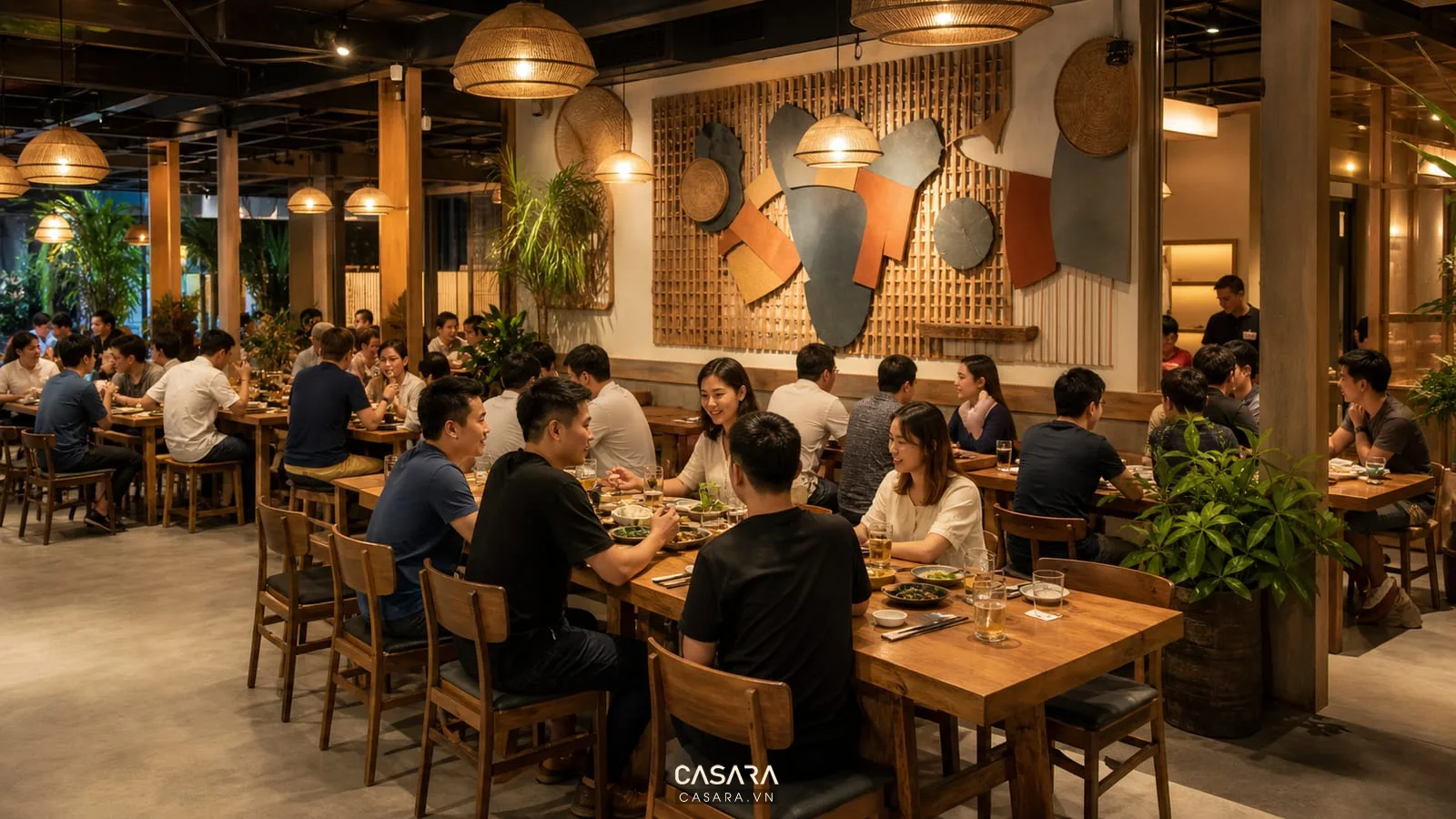 Không gian quán nhậu với bàn gỗ dài, ghế gỗ, đèn thả ánh sáng ấm và mảng tường trang trí biển hiệu gần khu ăn uống.