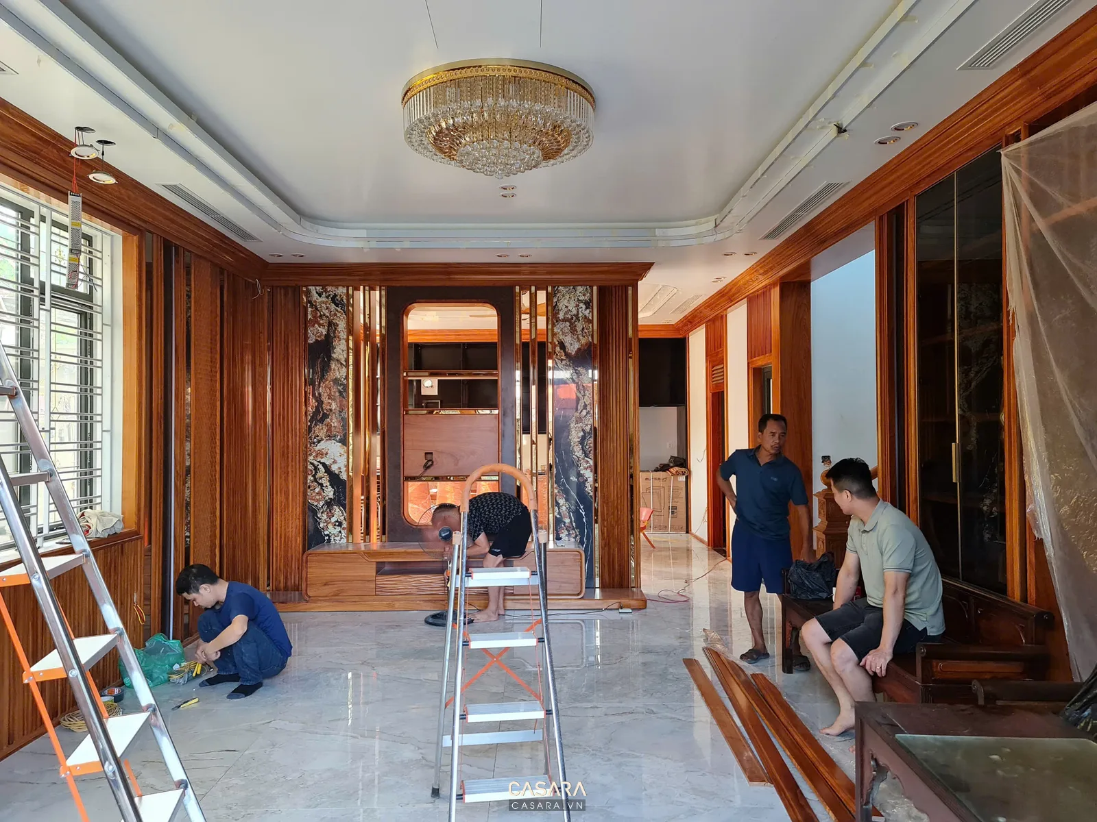 Không gian phòng khách đang thi công nội thất gỗ với kệ tivi và vách trang trí