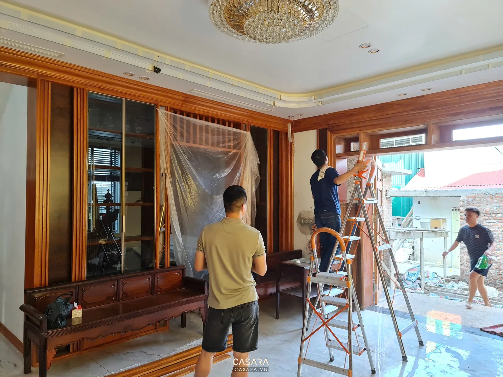 Đội thợ đang lắp đặt nội thất gỗ trong phòng khách